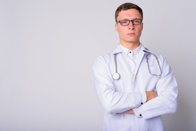 Ritratto di giovane uomo medico indossando occhiali da vista contro il muro bianco