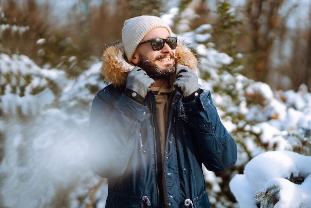 Ritratto di giovane uomo nella foresta invernale innevata Stagione Natale viaggio e concetto di persone