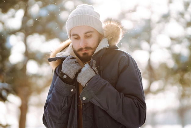 Ritratto di giovane uomo nella foresta invernale innevata Stagione Natale viaggio e concetto di persone