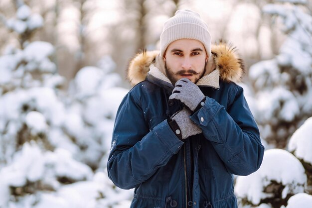 Ritratto di giovane uomo nella foresta invernale innevata Stagione Natale viaggio e concetto di persone