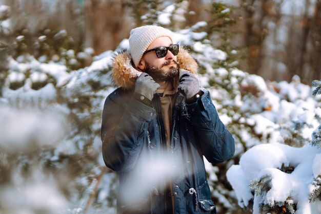 Ritratto di giovane uomo nella foresta invernale innevata Stagione Natale viaggio e concetto di persone