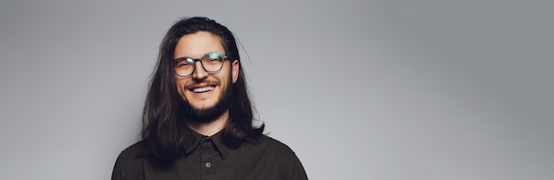 Ritratto di giovane uomo sorridente con capelli lunghi e occhiali Banner panoramico