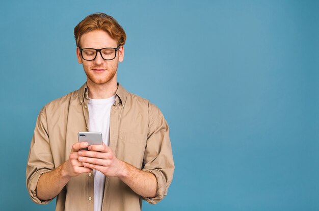 ritratto di giovane uomo sorridente felice nella digitazione casuale degli sms. usando il telefono.