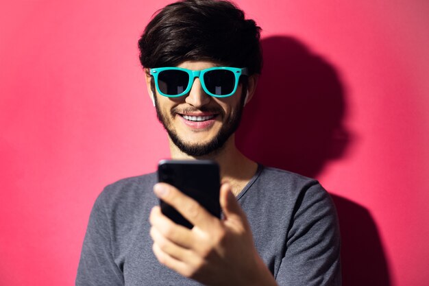 Ritratto di giovane uomo sorridente utilizza lo smartphone