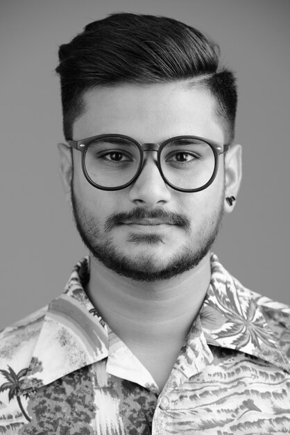Ritratto di giovane uomo turistico indiano barbuto bello su bianco in bianco e nero