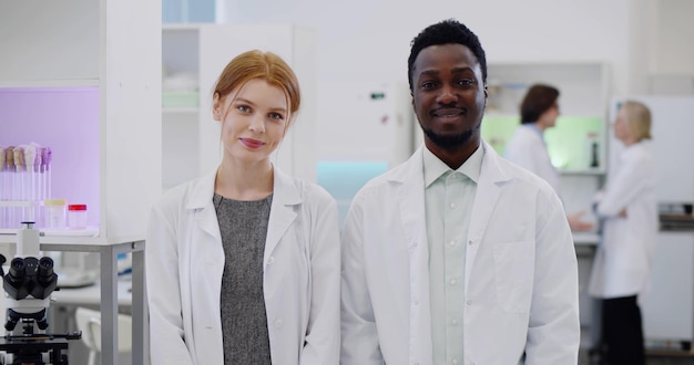 Ritratto di giovani scienziati multietnici che sorridono alla macchina fotografica in laboratorio moderno