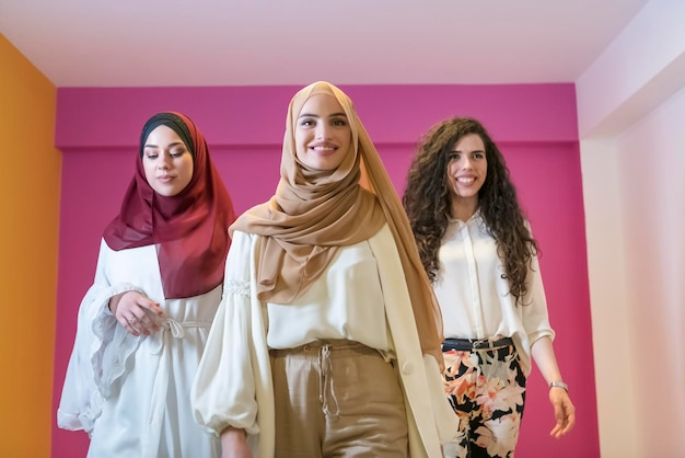 Ritratto di gruppo di belle donne musulmane due di loro in un abito alla moda con hijab isolato su uno sfondo rosa. Foto di alta qualità