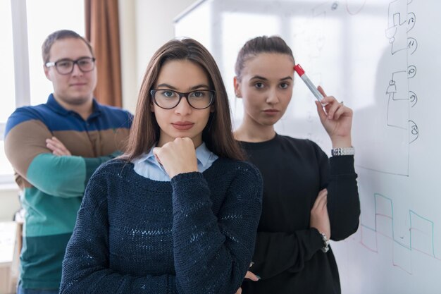 ritratto di gruppo di giovani studenti in piedi davanti alla lavagna bianca e guardando la telecamera