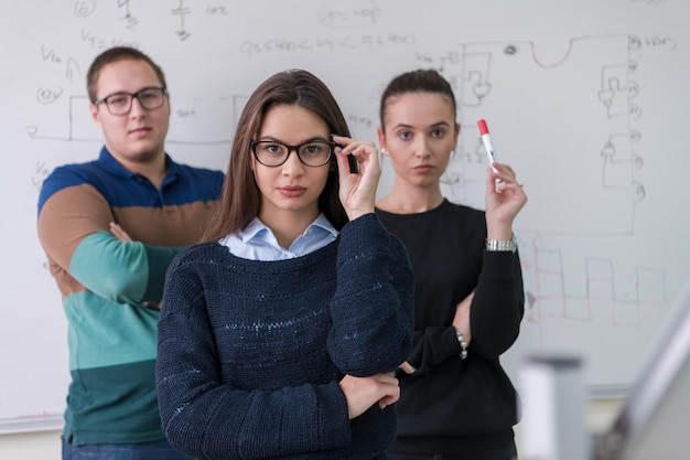 ritratto di gruppo di giovani studenti in piedi davanti alla lavagna bianca e guardando la telecamera