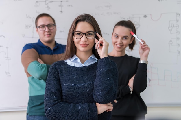 ritratto di gruppo di giovani studenti in piedi davanti alla lavagna bianca e guardando la telecamera