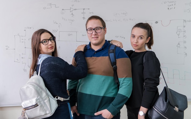 ritratto di gruppo di giovani studenti in piedi davanti alla lavagna bianca e guardando la telecamera