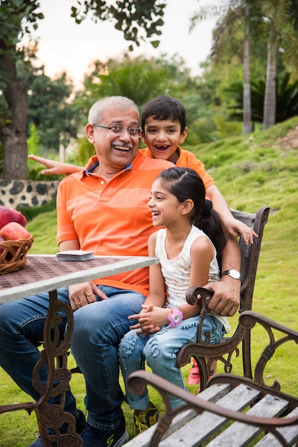 Ritratto di Happy Indian Asian Kids e nonno seduti su una sedia a sdraio