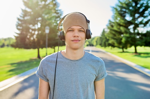 Ritratto di hipster adolescente in cappello lavorato a maglia con le cuffie che guardano a porte chiuse