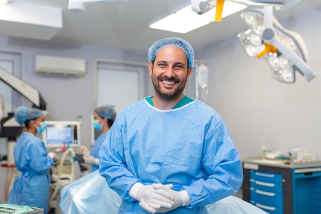 Ritratto di infermiere chirurgo o membro del personale vestito con maschera chirurgica per camice e retina per capelli nel teatro della sala operatoria dell'ospedale rendendo il contatto visivo sorridente soddisfatto felice guardando la fotocamera