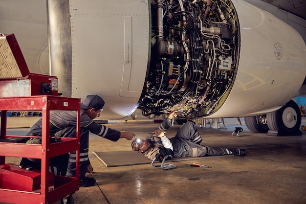 Ritratto di ingegnere aeronautico nell'hangar che ripara e mantiene il motore a reazione dell'aeroplano