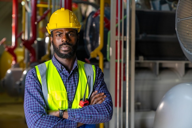 Ritratto di ingegnere elettrico professionista in uniforme di sicurezza che lavora nella sala di controllo del sito della fabbrica Tecnico industriale che controlla e mantiene il sistema di alimentazione di produzione nella sala dell'impianto