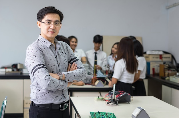 Ritratto di insegnante asiatico davanti a studenti universitari in classe laboratorio