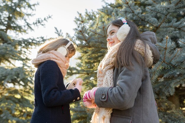 Ritratto di inverno all'aperto di due bambine vicino all'albero di Natale.