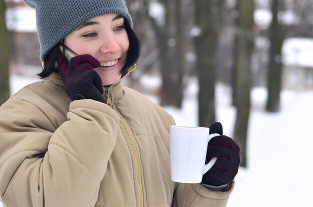 Ritratto di inverno della ragazza con smartphone e tazza di caffè