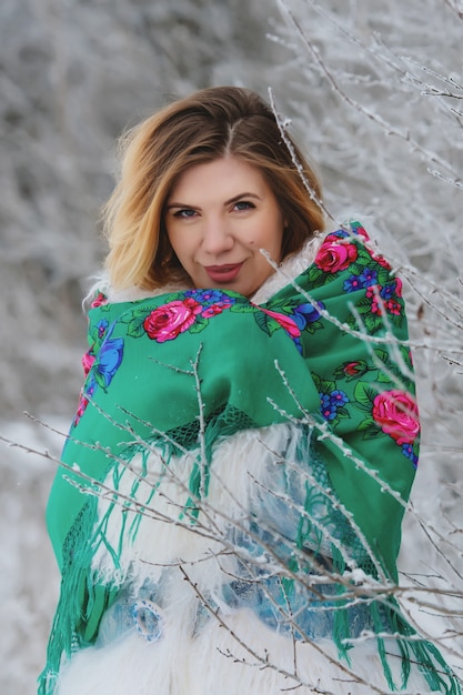 Ritratto di inverno di giovane donna sorridente nel bosco innevato.