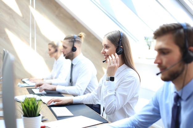 Ritratto di lavoratore call center accompagnato dal suo team. Operatore di assistenza clienti sorridente al lavoro.