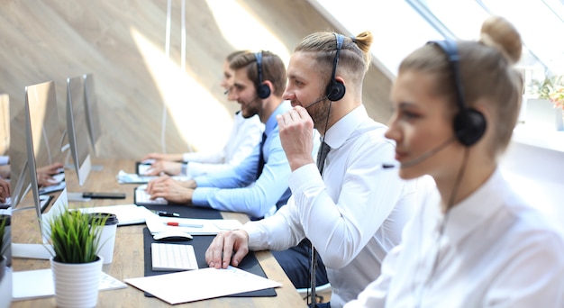 Ritratto di lavoratore call center accompagnato dal suo team. Operatore di assistenza clienti sorridente al lavoro.