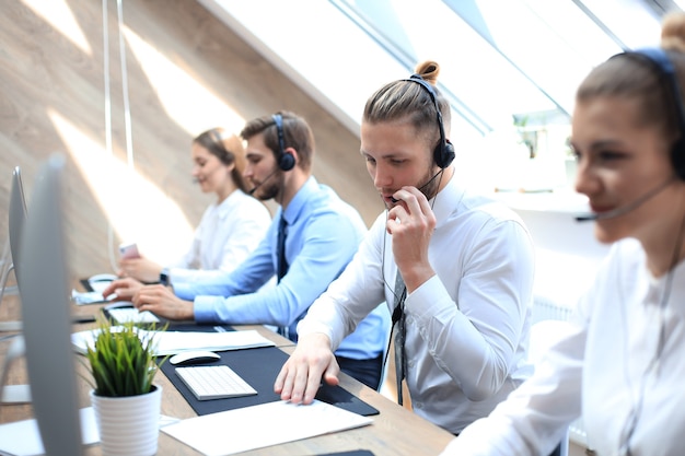 Ritratto di lavoratore call center accompagnato dal suo team. Operatore di assistenza clienti sorridente al lavoro.