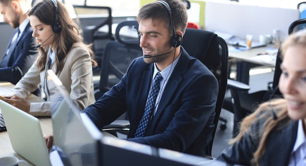 Ritratto di lavoratore call center accompagnato dal suo team. Operatore di assistenza clienti sorridente al lavoro.