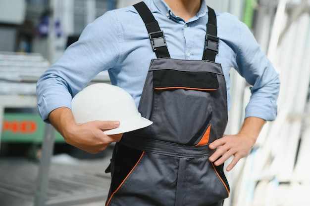 Ritratto di lavoratore sorridente in piedi dalla macchina di produzione industriale