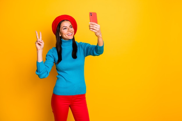 Ritratto di lei bella attraente bella allegra ragazza allegra che fa prendendo selfie divertendosi mostrando v-segno godendo il fine settimana di viaggio isolato sopra la parete di colore giallo vibrante brillante brillante brillantezza