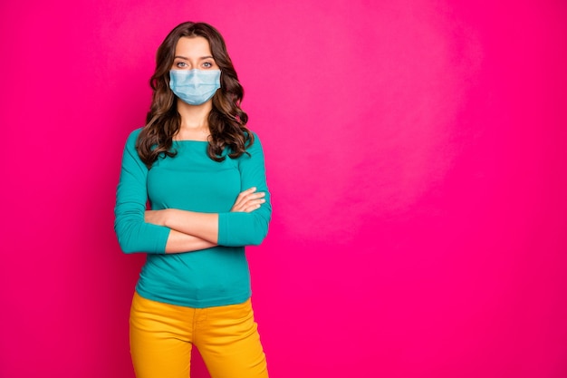 Ritratto di lei bella ragazza attraente dai capelli ondulati che indossa maschera di garza di sicurezza braccia conserte fermare l'infezione pandemia concetto copia spazio isolato fucsia colore brillante sfondo