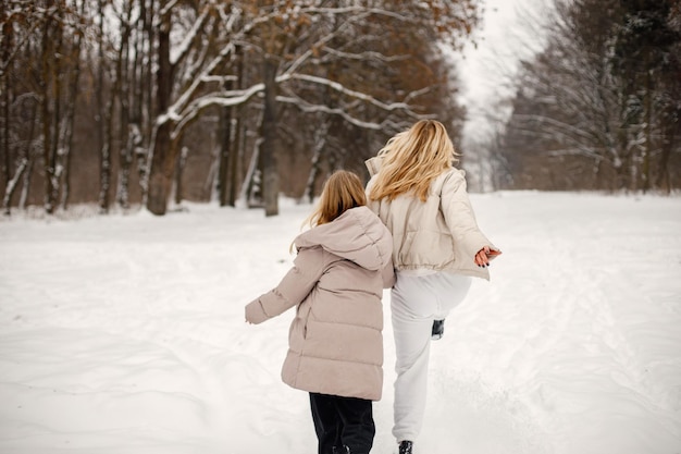 Ritratto di madre bionda e figlia adolescente in piedi nella foresta d'inverno