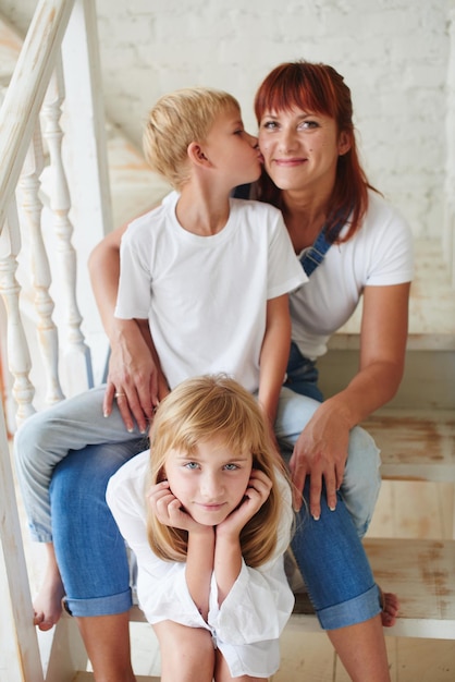 Ritratto di madre con figlia e figlio seduti sulle scale a casa