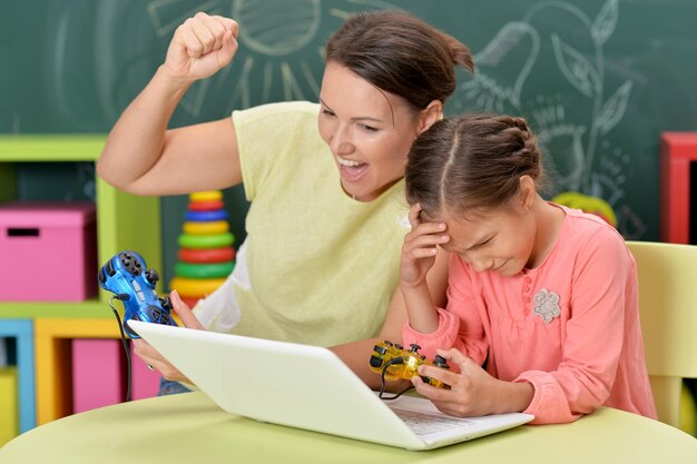 Ritratto di madre con la piccola figlia che gioca ai giochi per computer