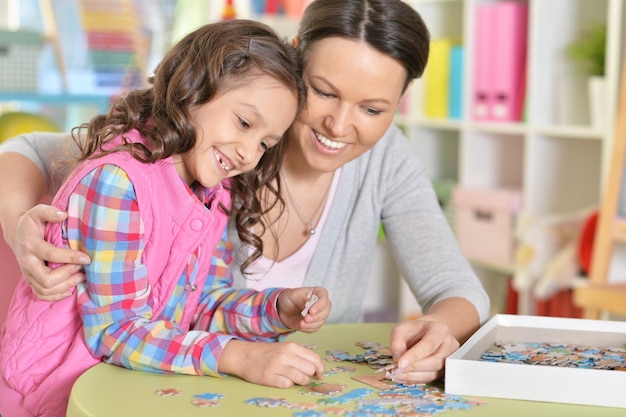 Ritratto di madre con la piccola figlia che raccoglie puzzle