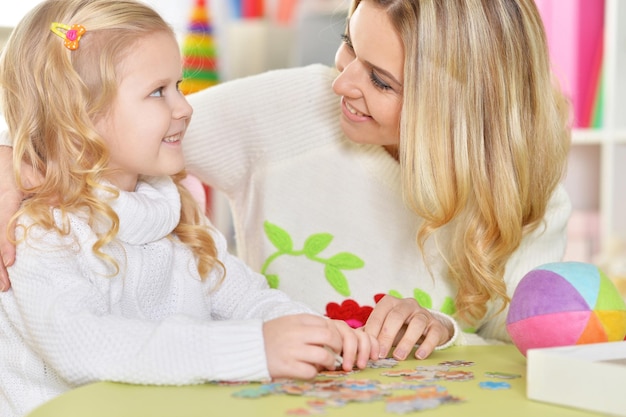 Ritratto di madre con piccola figlia che raccoglie puzzle