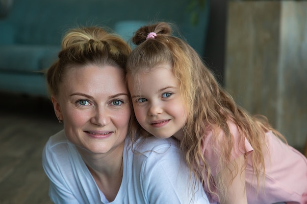 ritratto di madre e figlia in abiti sportivi che abbracciano e guardano la telecamera.