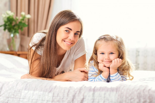 Ritratto di madre e figlia sul letto vicino alla finestra.