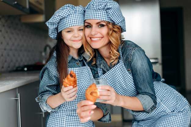 Ritratto di madre e figlia tenendo cornetti e latte e guardando la telecamera