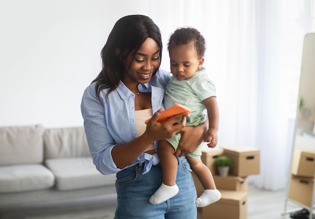 Ritratto di mamma afroamericana che utilizza il cellulare a casa