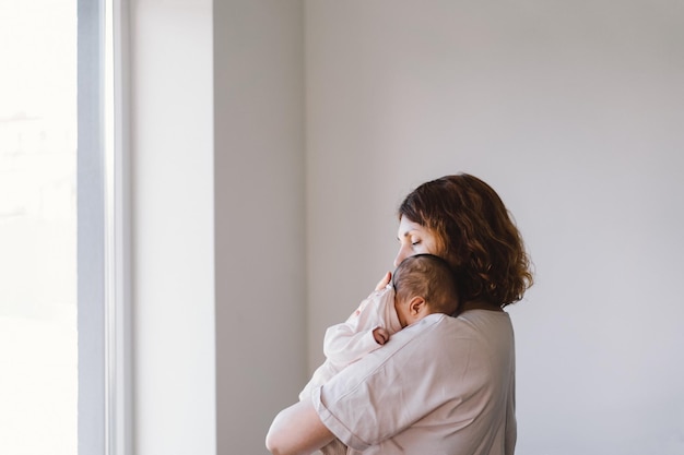 Ritratto di mamma felice che tiene il bambino sulle mani Mamma amorevole che si prende cura del suo neonato a casa Madre che abbraccia la sua bambina di 1 mese