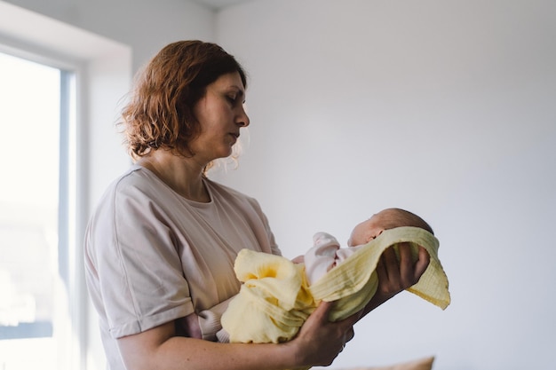 Ritratto di mamma felice che tiene il bambino sulle mani Mamma amorevole che si prende cura del suo neonato a casa Madre che abbraccia la sua bambina di 1 mese