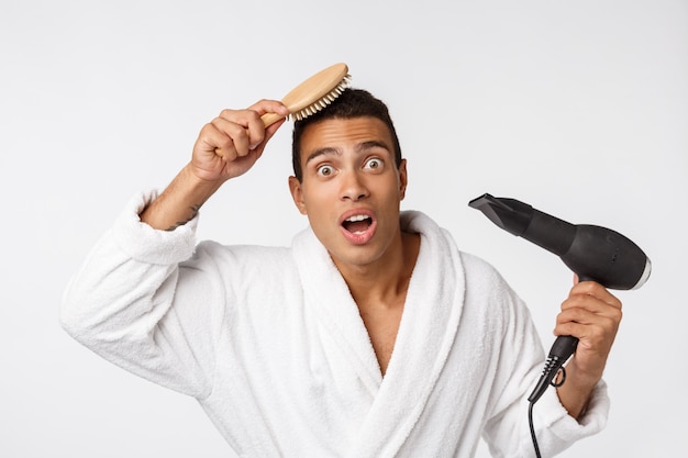 Ritratto di maturo divertente bel ragazzo dalla pelle abbronzata con capelli ricci in accappatoio bianco casual