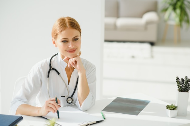 Ritratto di medico femminile attraente che tiene appunti mentre levandosi in piedi in clinica