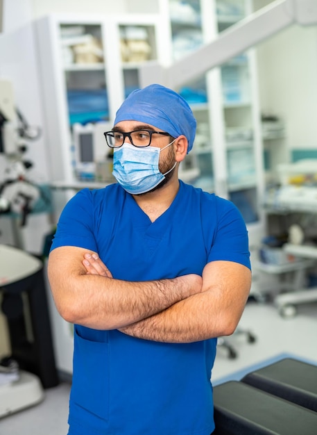 Ritratto di medico maschio anziano in piedi con le braccia incrociate presso l'ufficio del medico e guardando la fotocamera Volto premuroso del medico esperto