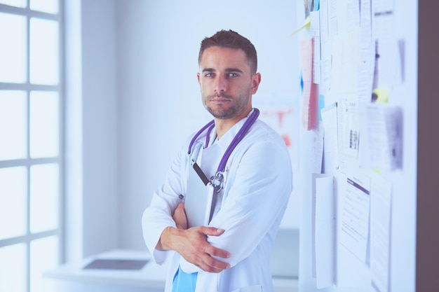 Ritratto di medico maschio giovane e fiducioso in piedi in studio medico