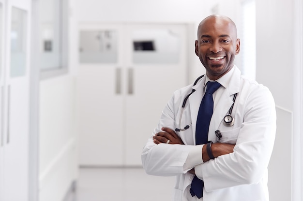 Ritratto di medico maschio maturo che indossa camice bianco in piedi nel corridoio dell'ospedale