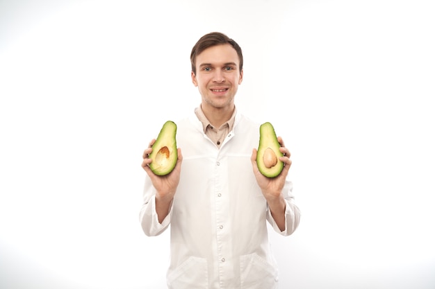 Ritratto di medico nutrizionista maschio sorridente positivo con avocado.