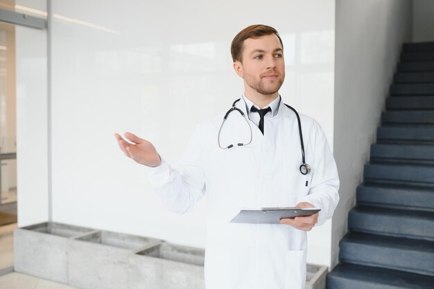 Ritratto di medico sorridente in uniforme in piedi nella sala della clinica di medicina