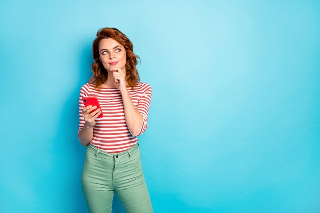 Ritratto di mentalità ispirata ragazza dipendente dai social media utente usa il cellulare pensa pensieri post commento indossare pullover elegante isolato su colore blu